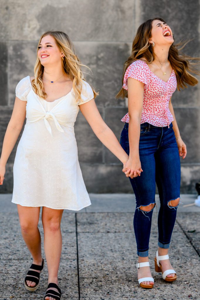 High school senior sisters holding hands and laughing for their 4th of July Model Team Photoshoot