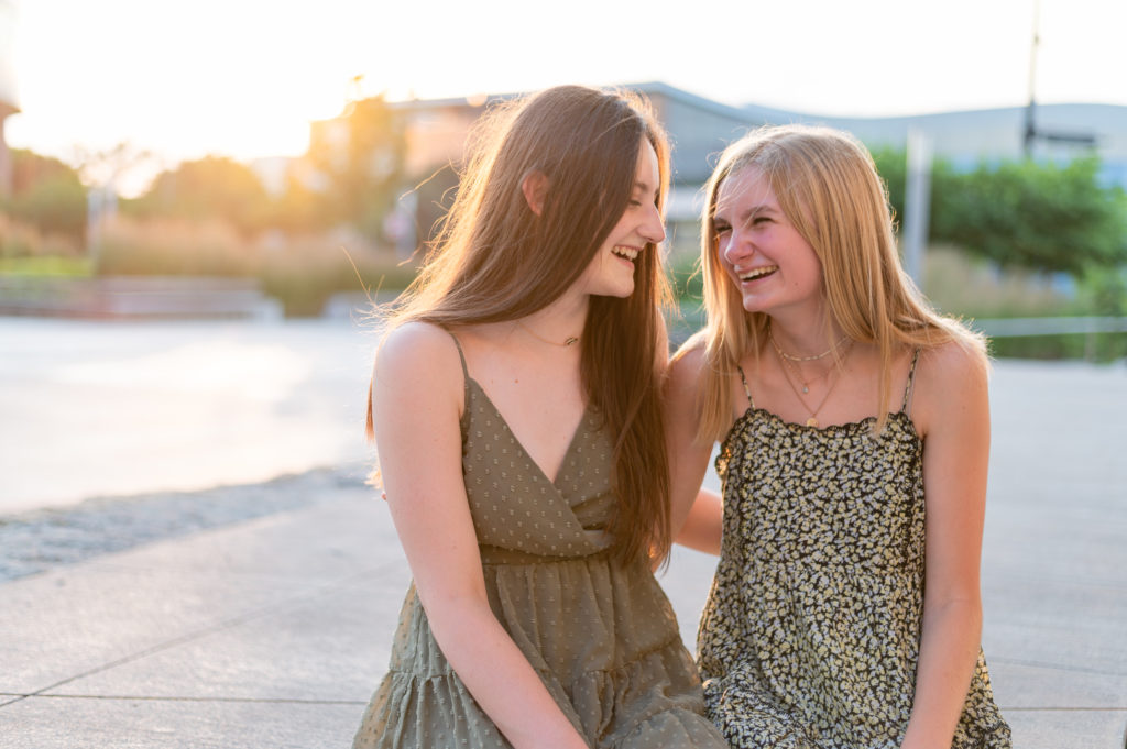 Two High School Senior Girls in cute sun dresses talking and laughing