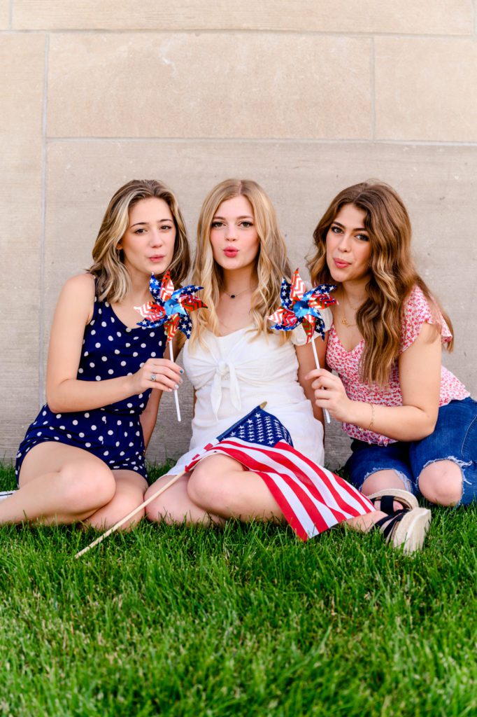 3 High School senior girls blowing on pinwheels for 4th of July model team photoshoot